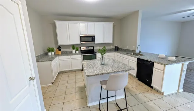 a kitchen with granite countertop a sink stove and white cabinets