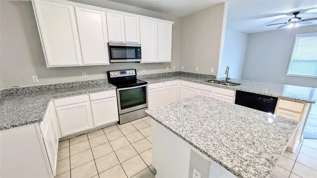a kitchen with granite countertop white cabinets and stainless steel appliances