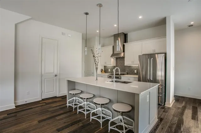 a kitchen with stainless steel appliances a dining table chairs sink and wooden floor