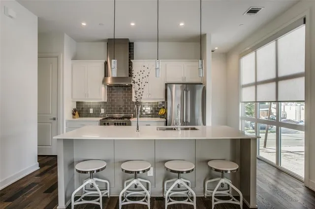 a kitchen with stainless steel appliances a dining table chairs sink and cabinets