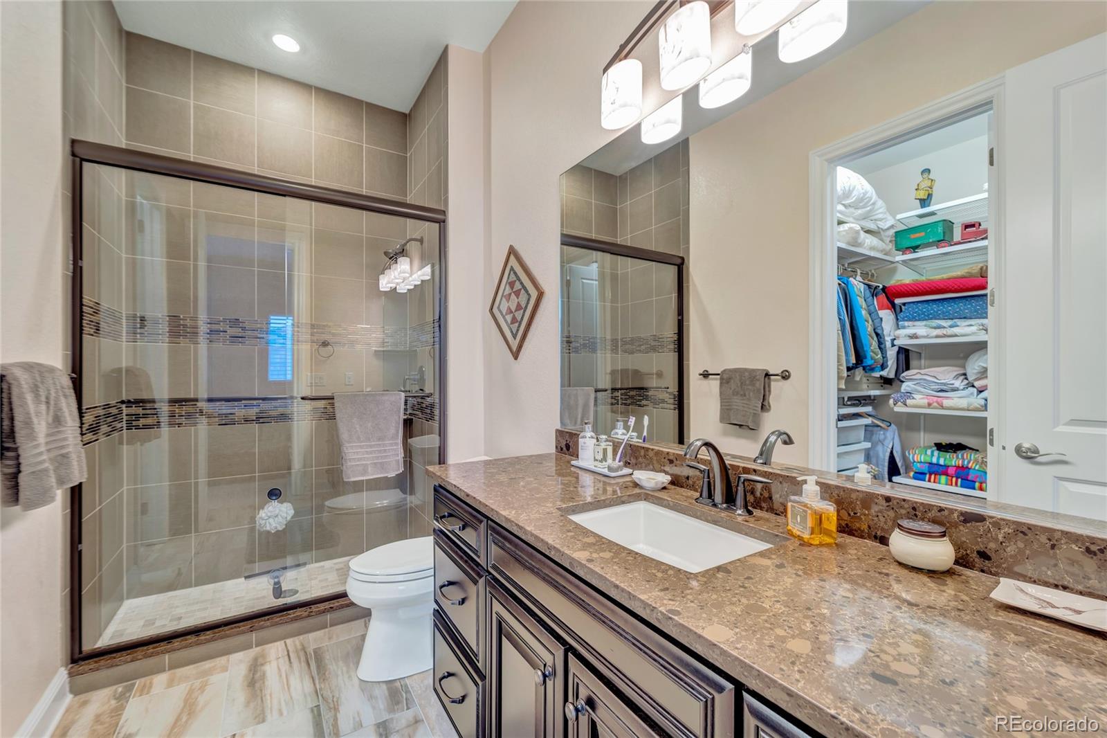 15653 Deer Mountain Circle Broomfield, CO 80023 - Photo 30 of 37 a bathroom with a granite countertop sink a toilet and shower
