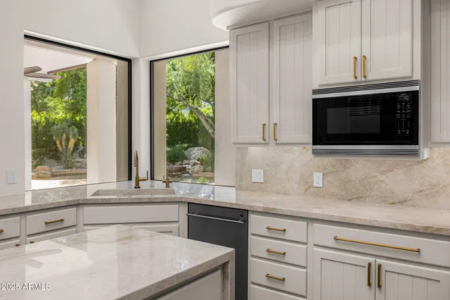 a kitchen with granite countertop white cabinets and a window