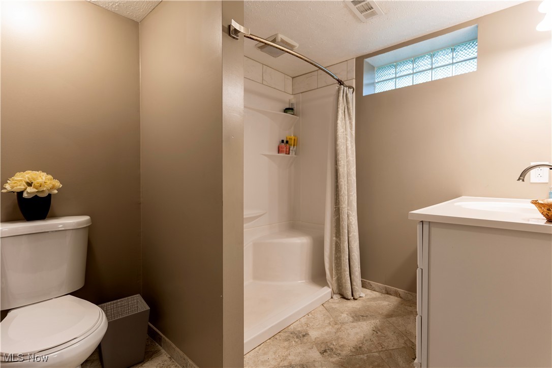 1400 East Miner Road Cleveland, OH 44124 - Photo 21 of 25 Bathroom featuring a textured ceiling, toilet, vanity, and curtained shower