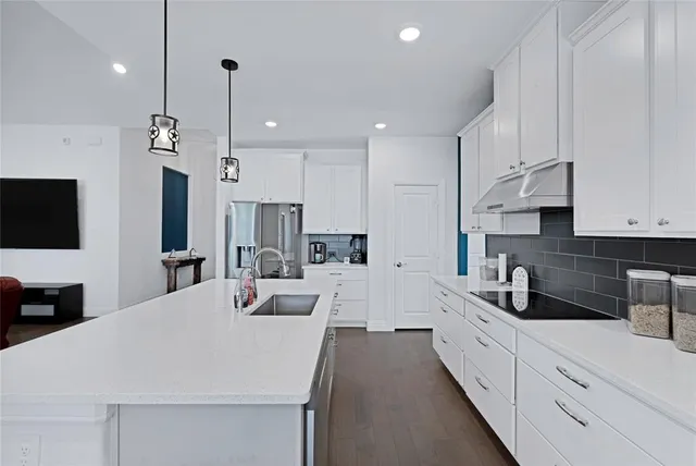 a large kitchen with kitchen island white cabinets and stainless steel appliances