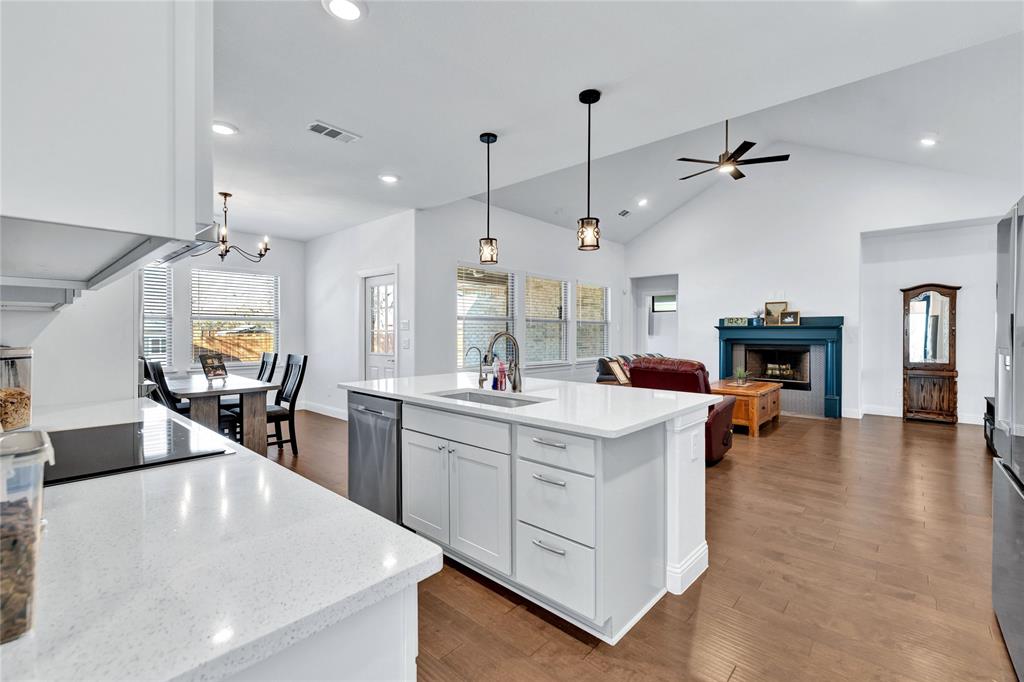 137 Gardenia Drive Azle, TX 76020 - Photo 13 of 38 Kitchen with white cabinets, dark wood-style flooring, a fireplace, a kitchen island with sink, and light stone countertops