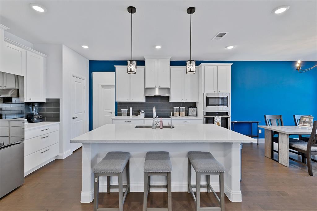 137 Gardenia Drive Azle, TX 76020 - Photo 10 of 38 Kitchen featuring a kitchen bar, hanging light fixtures, white cabinets, stainless steel appliances, and an island with sink