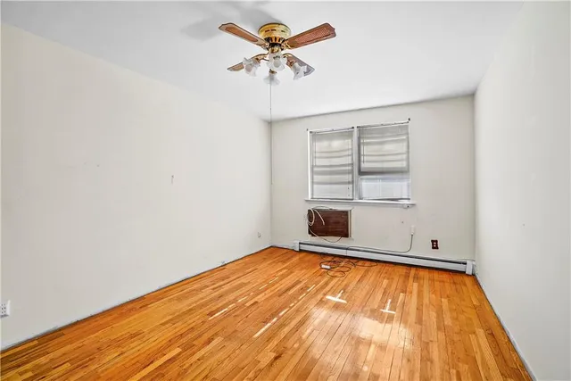 an empty room with a chandelier fan and windows