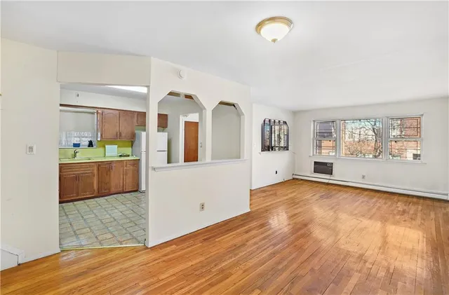 a view of a living room with kitchen island wooden floor and appliances