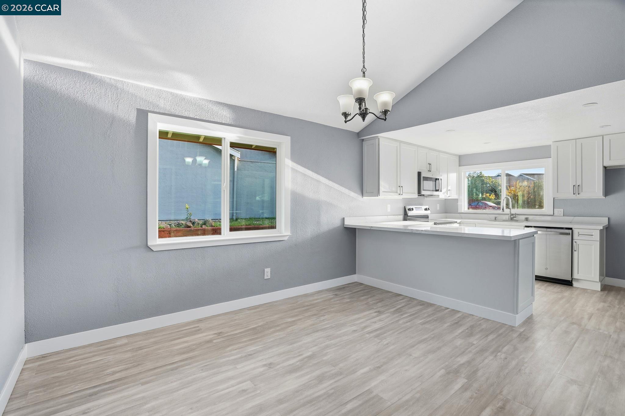 834 Coral Ridge Circle Rodeo, CA 94572 - Photo 9 of 32 a large white kitchen with kitchen island a stove a sink dishwasher and a fireplace with wooden floor