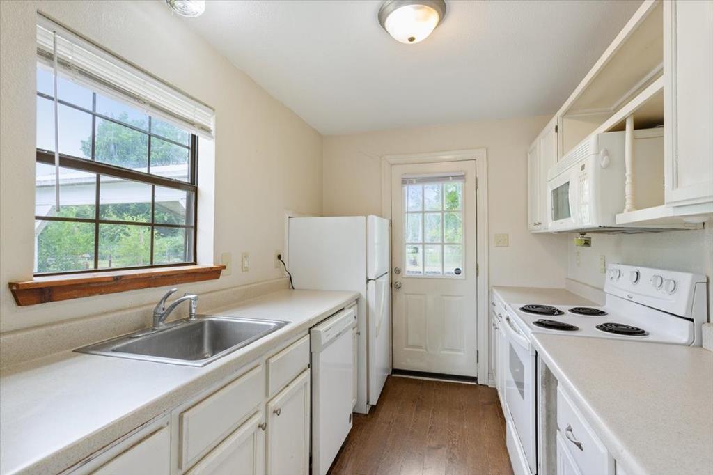 608 9th Street Hico, TX 76457 - Photo 7 of 23 Kitchen featuring white cabinetry, light-toned countertops, a stainless steel sink, and wood-finish flooring