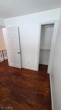 a view of an empty room with wooden floor and closet