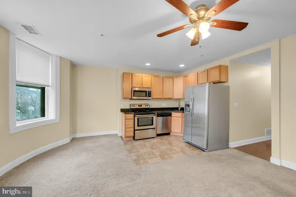 a kitchen with stainless steel appliances kitchen island granite countertop a refrigerator and a stove top oven