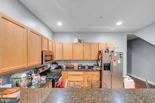a kitchen with stainless steel appliances granite countertop a refrigerator and a stove top oven