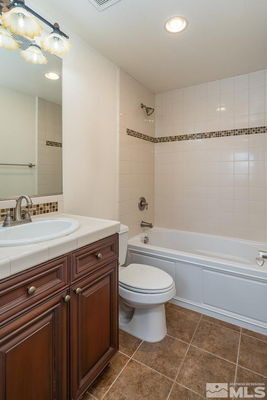 1935 Angel Ridge Drive Reno, NV 89521 - Photo 26 of 33 a bathroom with a granite countertop sink a toilet a mirror and bathtub