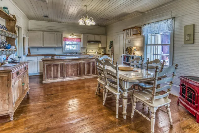 a kitchen with stainless steel appliances granite countertop a stove top oven a sink dishwasher a dining table and chairs with wooden floor