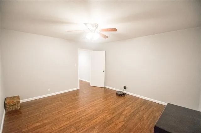 an empty room with wooden floor and fan
