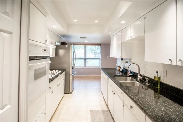 a kitchen with granite countertop a sink a counter top space stainless steel appliances and cabinets