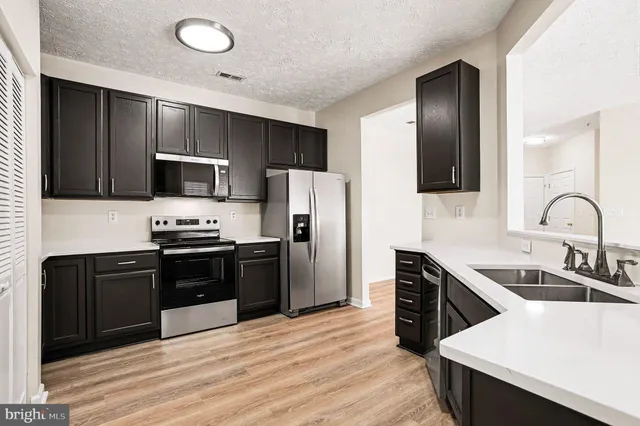 a kitchen with granite countertop a refrigerator and a stove top oven