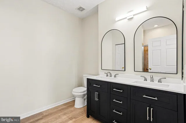 a bathroom with a granite countertop toilet a sink and a mirror