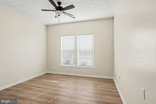 an empty room with a window and a ceiling fan