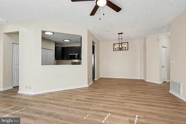 a view of a livingroom with a ceiling fan wooden floor and windows