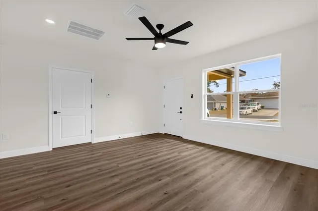 an empty room with wooden floor a ceiling fan and windows