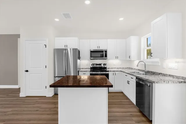 a kitchen with granite countertop a refrigerator and a stove top oven