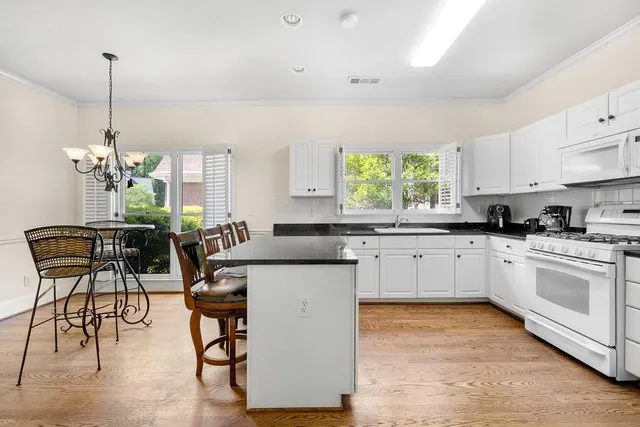 a kitchen with stainless steel appliances kitchen island granite countertop a stove a sink a dining table and chairs