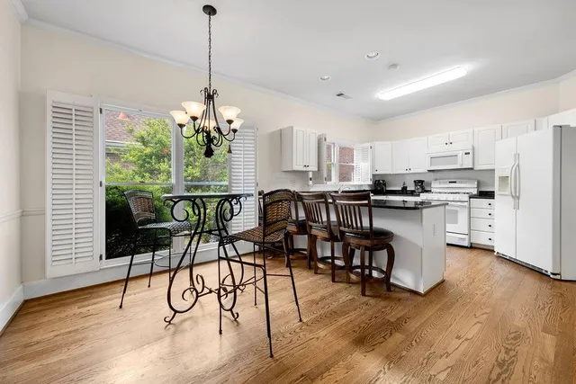 a kitchen with stainless steel appliances kitchen island granite countertop a stove a refrigerator a microwave oven a dining table and chairs with wooden floor