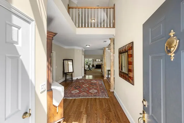 a view of a hallway to a livingroom with wooden floor and furniture