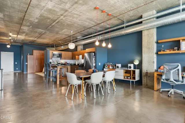 a dining hall with stainless steel appliances a dining table chairs and a living room view