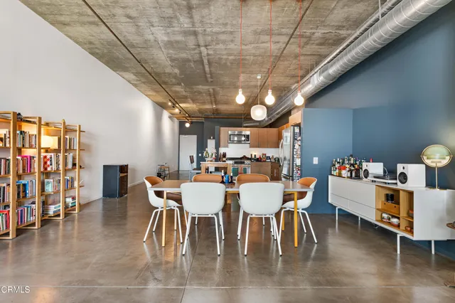 a dining room with stainless steel appliances a table chairs and a rug