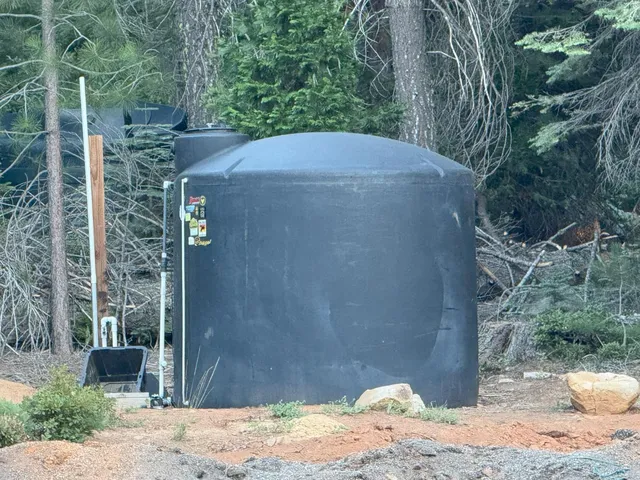 a backyard of a house with large trees and wooden fence