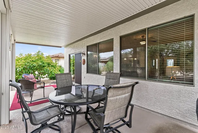 a patio with table and chairs and potted plants