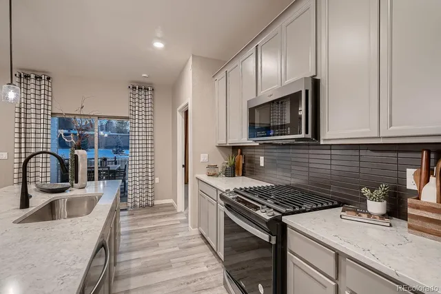 a kitchen with granite countertop a sink stainless steel appliances and cabinets