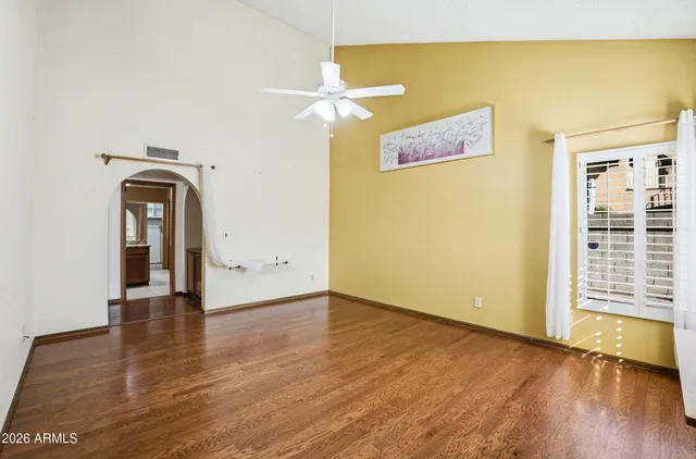 a view of empty room with wooden floor and fan