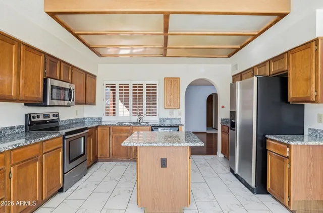 a large kitchen with stainless steel appliances granite countertop a stove refrigerator and cabinets