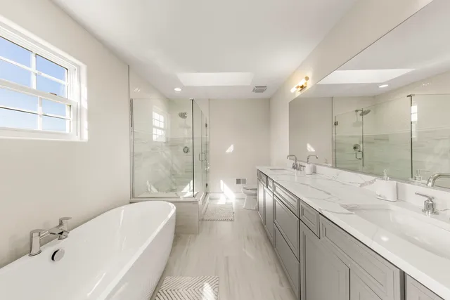 a spacious bathroom with a bathtub shower sink double and mirror
