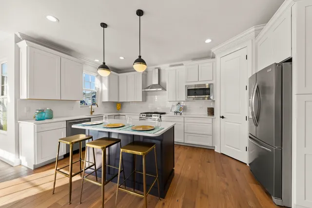 a kitchen with stainless steel appliances a stove a sink a refrigerator a center island and cabinets