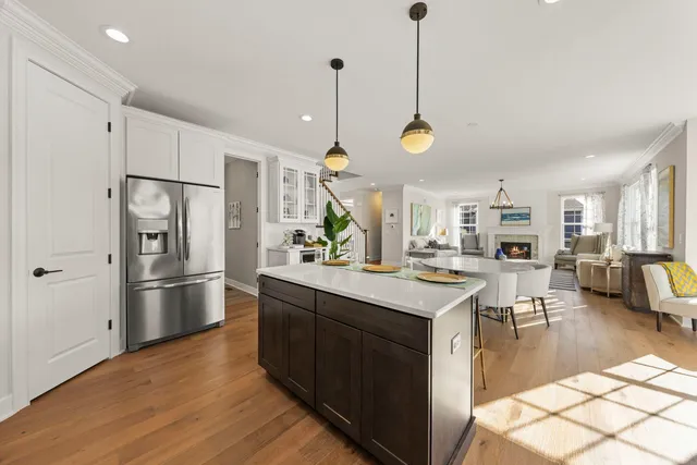 a kitchen with stainless steel appliances granite countertop a refrigerator a sink dishwasher a oven a dining table and chairs with wooden floor