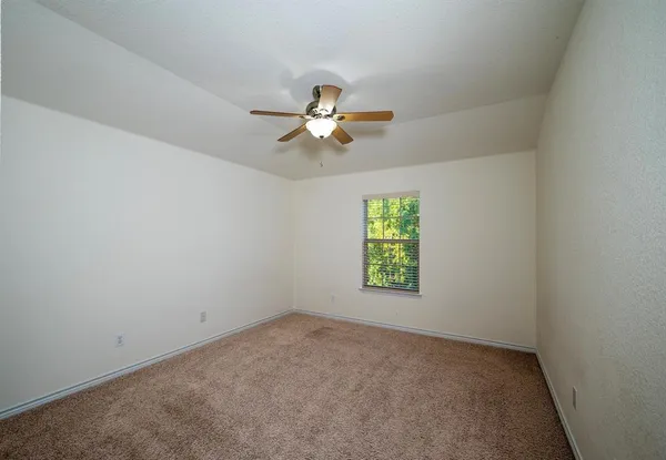an empty room with windows and fan