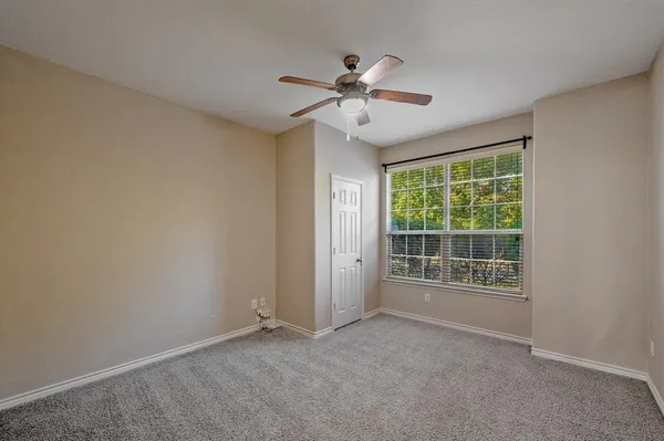 an empty room with chandelier fan and windows