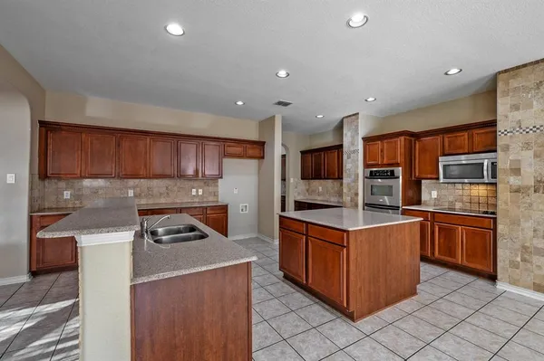 a kitchen with stainless steel appliances granite countertop a stove top oven a sink and a refrigerator
