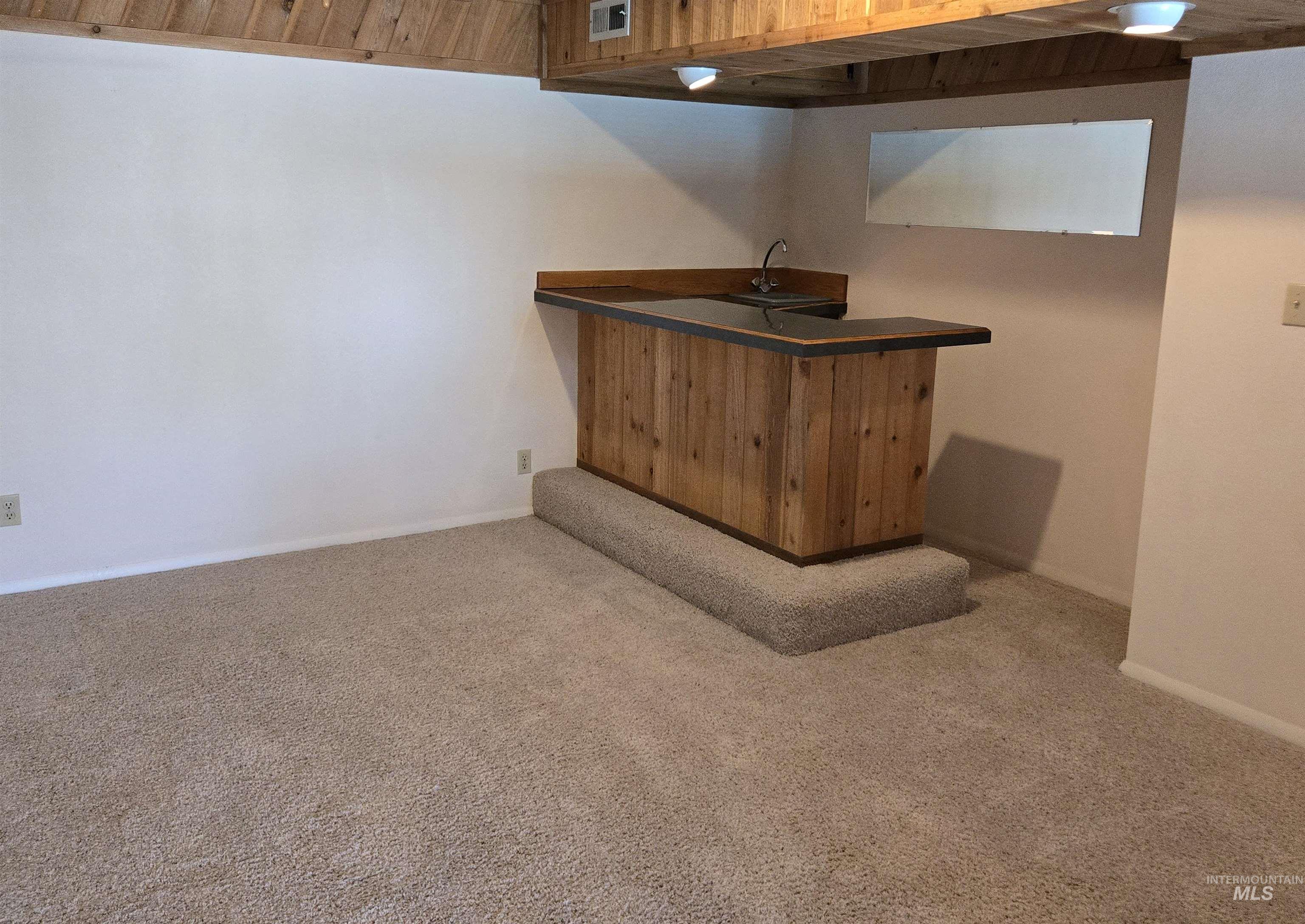 12050 West Hidden Valley Rim Road Boise, ID 83709 - Photo 17 of 39 Built-in wet bar with wood paneling, dark countertop, and integrated sink