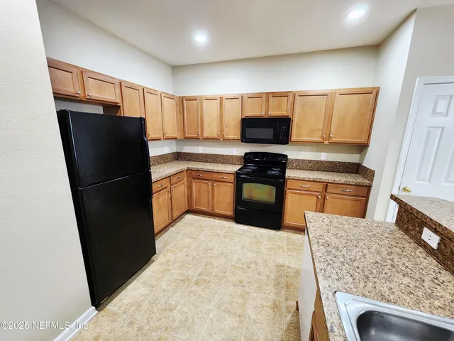 a kitchen with granite countertop a refrigerator stove and sink