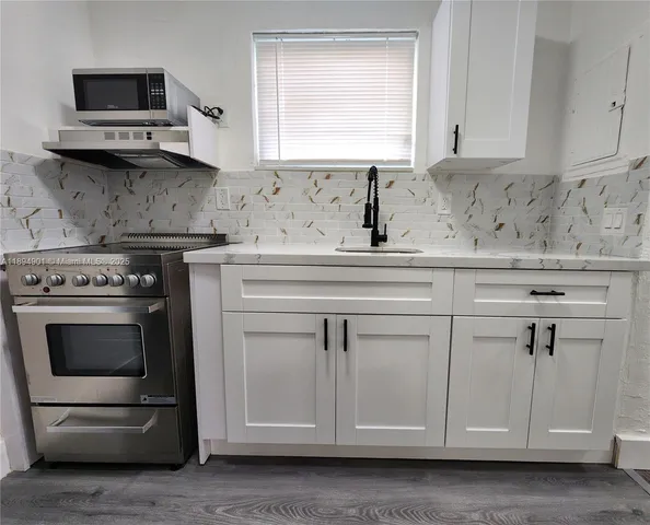 a kitchen with white cabinets and appliances