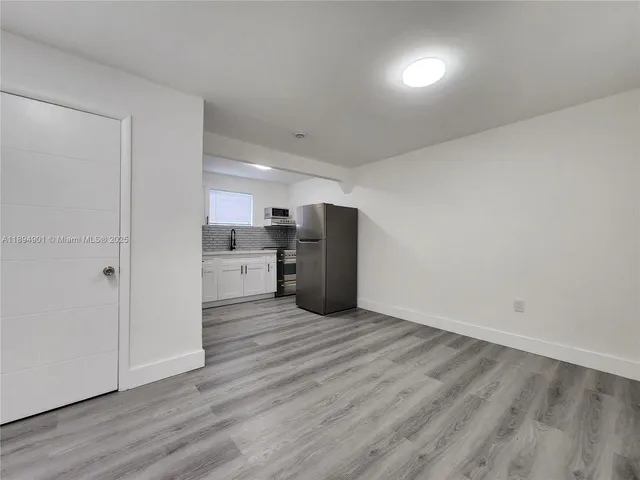 a view of an empty room with wooden floor and closet