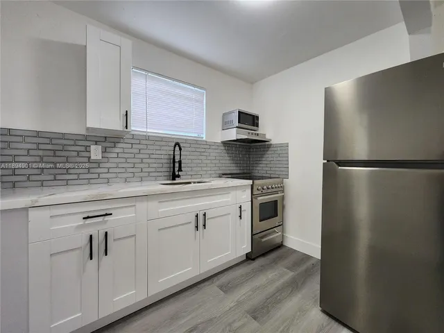 a kitchen with appliances a sink and cabinets