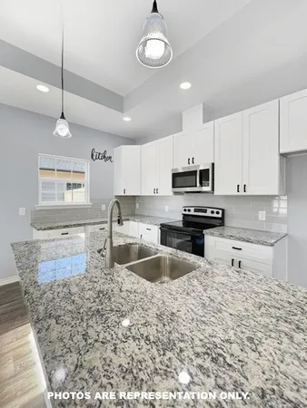 a kitchen with granite countertop a stove sink and microwave
