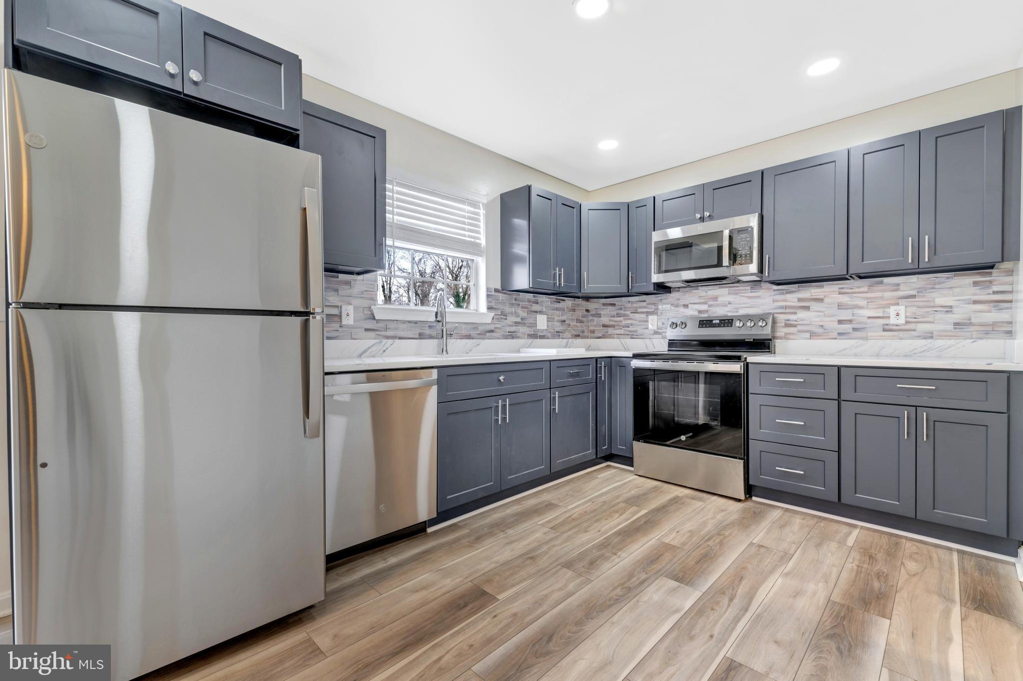 7108 Ruthgreen Road Windsor Mill, MD 21244 - Photo 12 of 25 a kitchen with stainless steel appliances granite countertop a refrigerator stove a sink dishwasher and wooden cabinets